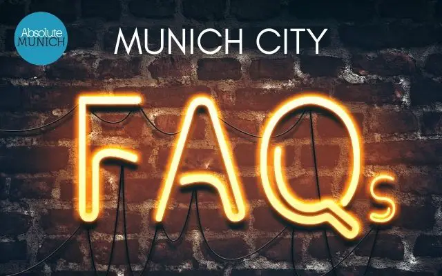 All About Munich FAQs shows a fluorescent FAQ sign on a brick wall