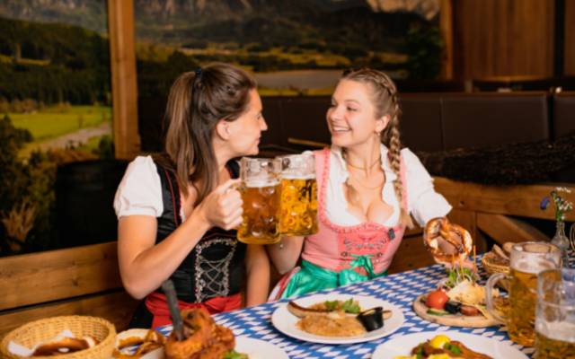 What is a dirndl at Oktoberfest featuring two women at an Oktoberfest table wearing dirndls