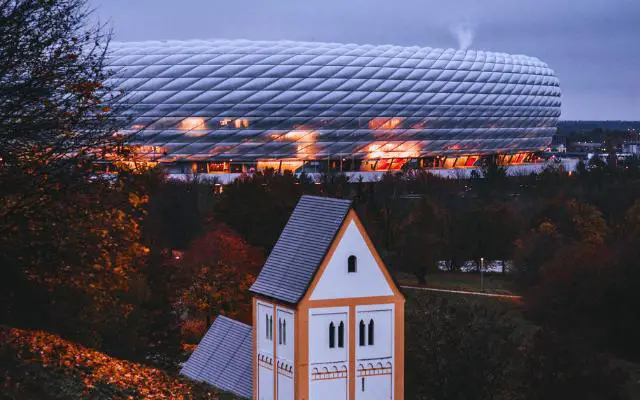 Allianz Arena Munich over the nearby hills with church in foreground