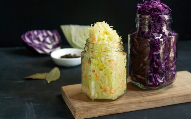 Sauerkraut Origin featuring overflowing jars with purple and white cabbage